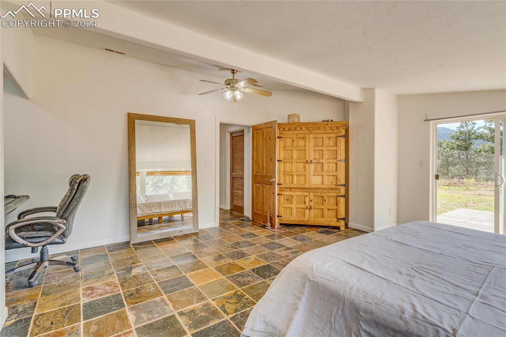 Tiled bedroom featuring access to outside, vaulted ceiling with beams, and ceiling fan