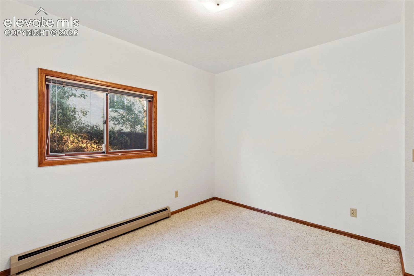 Interior room featuring neutral wall paint, carpeting, a window with wood-finish trim, and flush-mount ceiling lighting