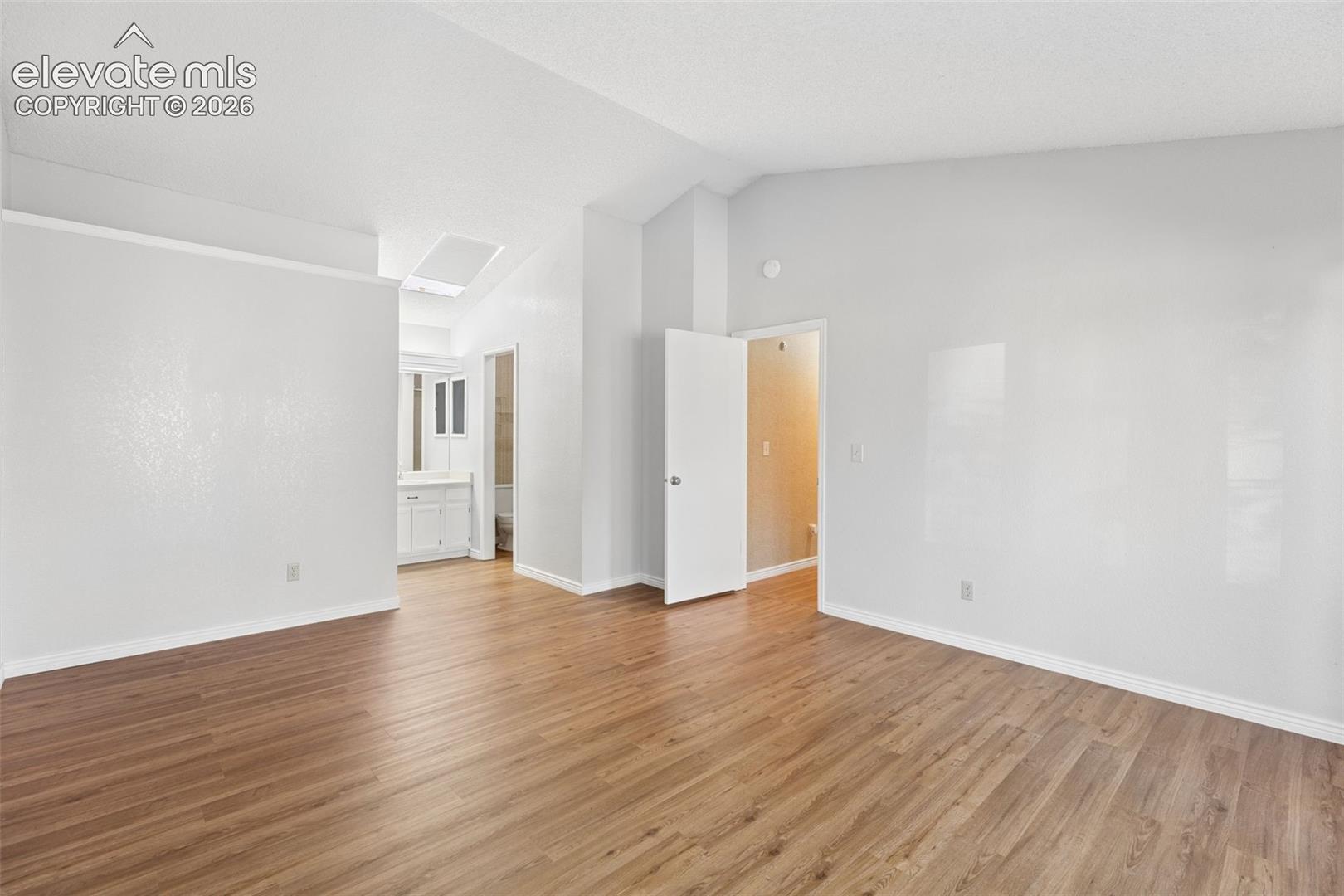 Vaulted ceilings, wood-finish flooring, and natural light from a skylight