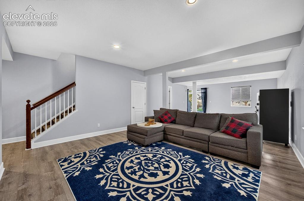 Wood-finish flooring throughout, recessed lighting, white trim, and a white interior door