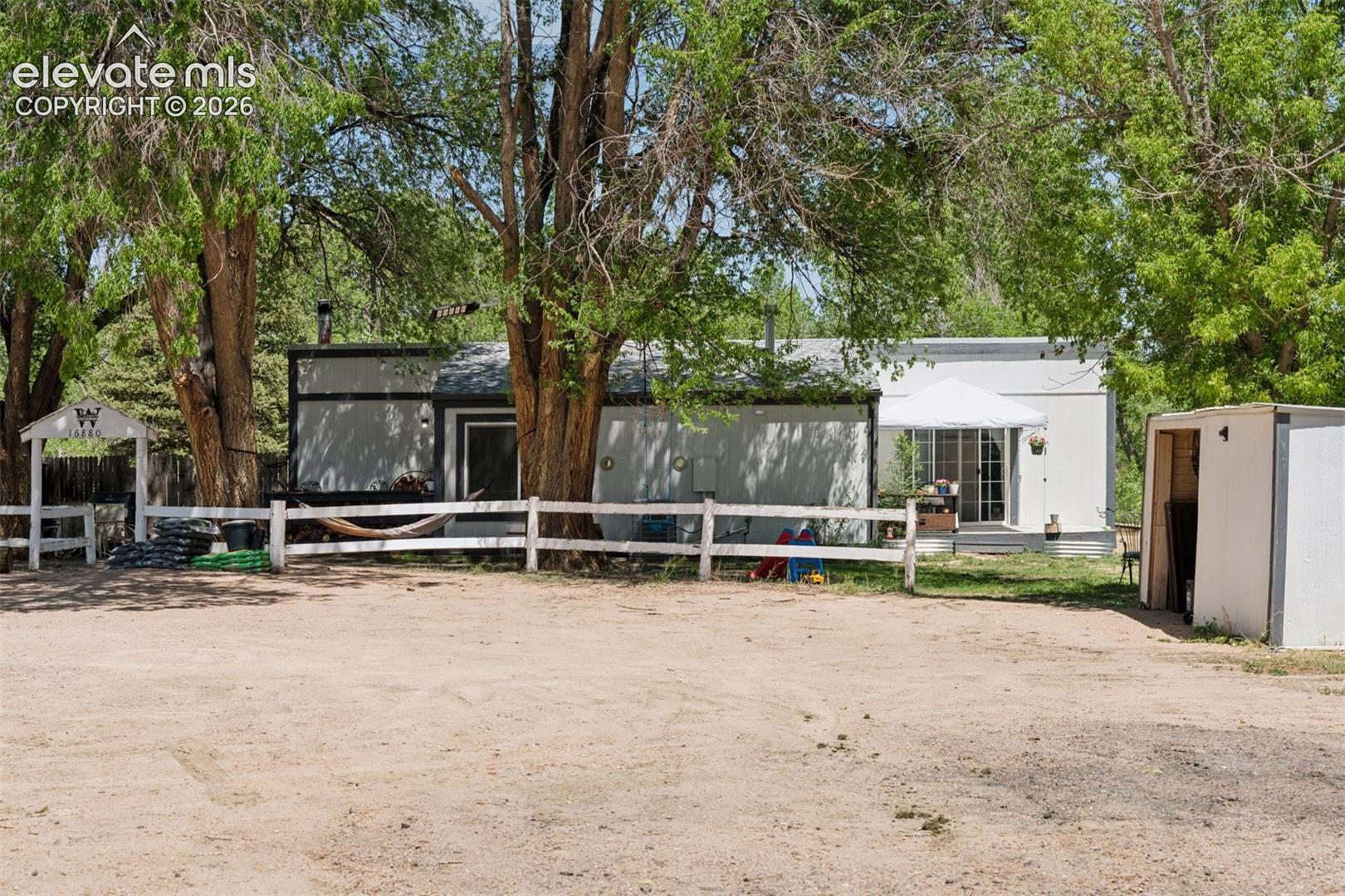 Exterior view of the second single-family residence featuring a 3-bedroom, 1-bath layout, set among mature trees on the property.