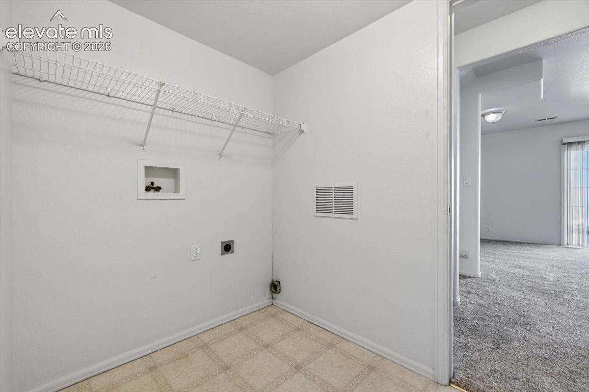 Laundry area featuring wire shelving, utility hookups, and tiled flooring