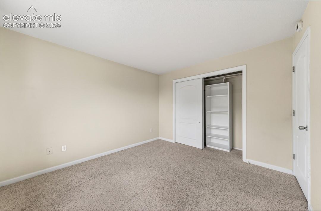 Neutral tone wall paint, light-toned carpet, white trim, sliding closet doors, and built-in shelving