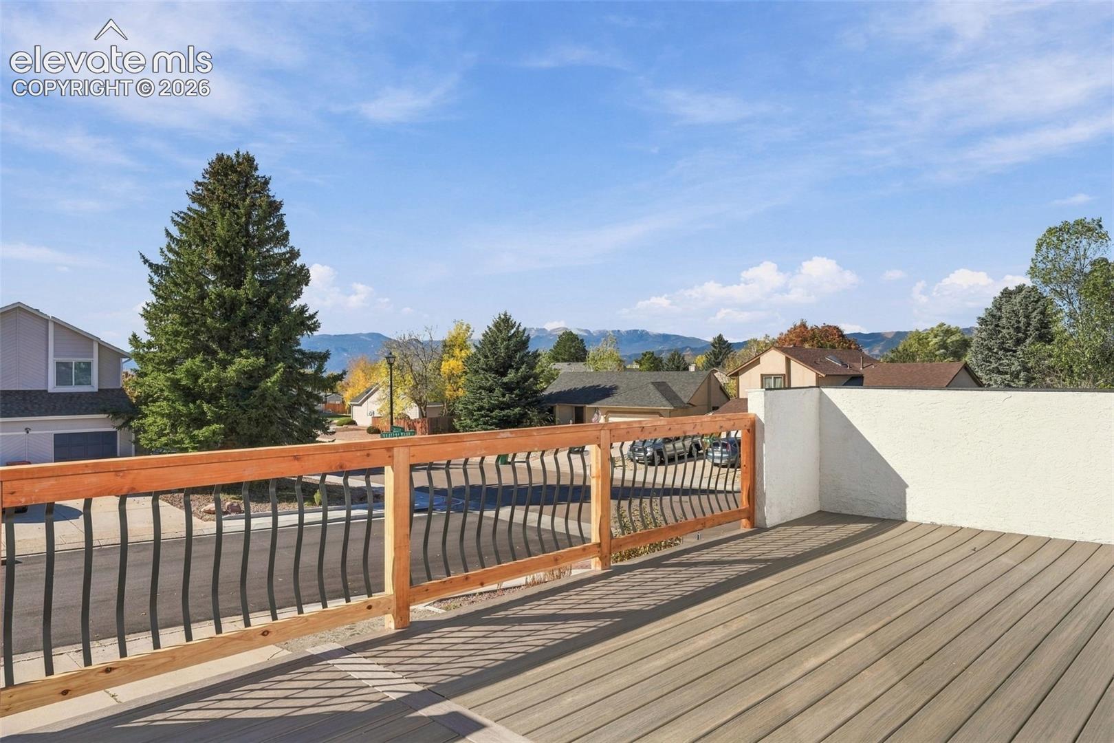 Elevated deck featuring composite decking, a wood-frame railing with vertical metal balusters, and mountain scenery