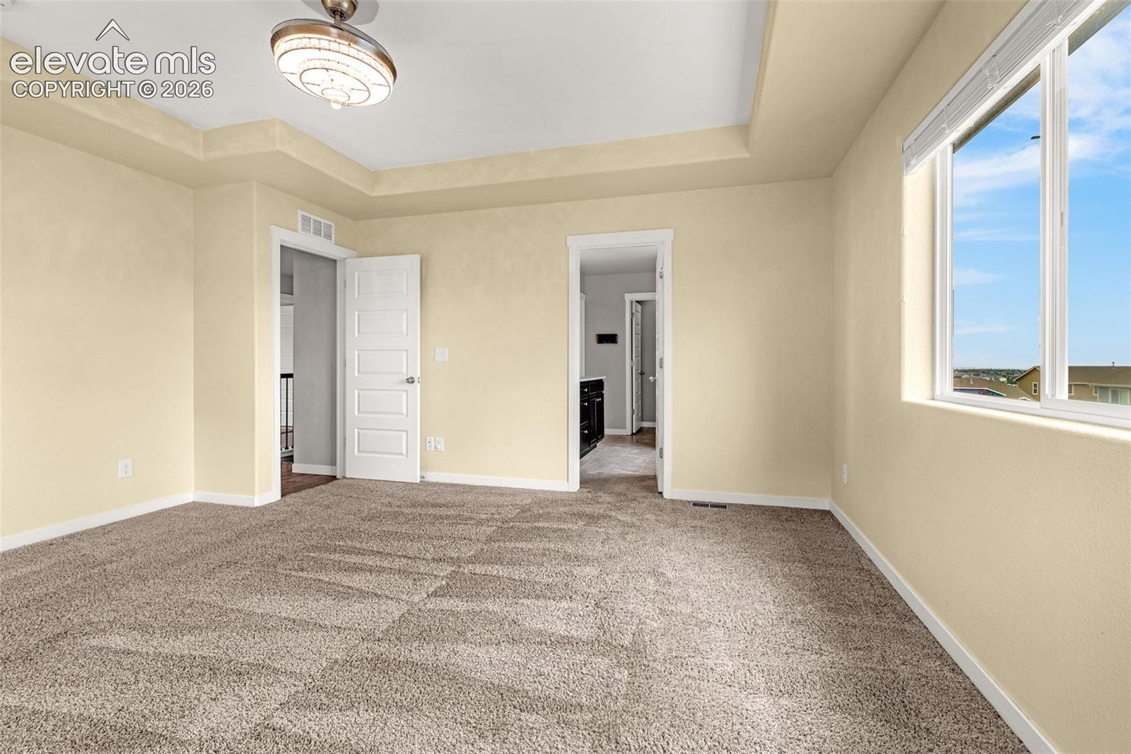 Recessed ceiling details, carpeted flooring, and a decorative ceiling fixture