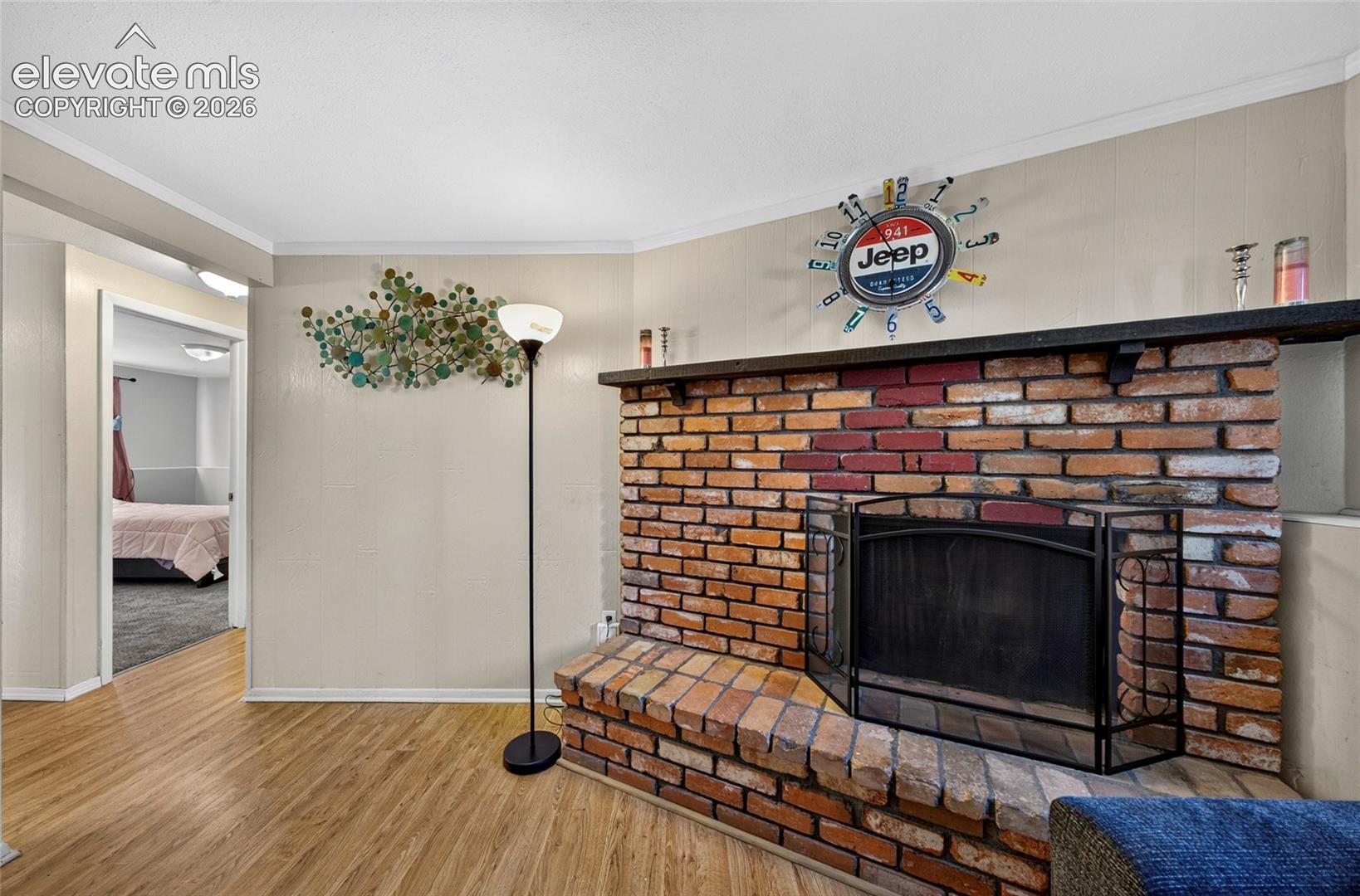 Floor-to-ceiling brick fireplace featuring a raised hearth and integrated timber mantelpiece, complemented by wood-finish flooring