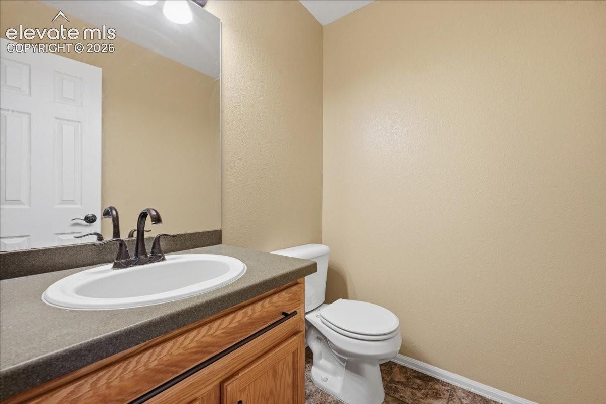 Vanity with a white oval sink, dark bronze-finish faucet, and wood-finish cabinetry