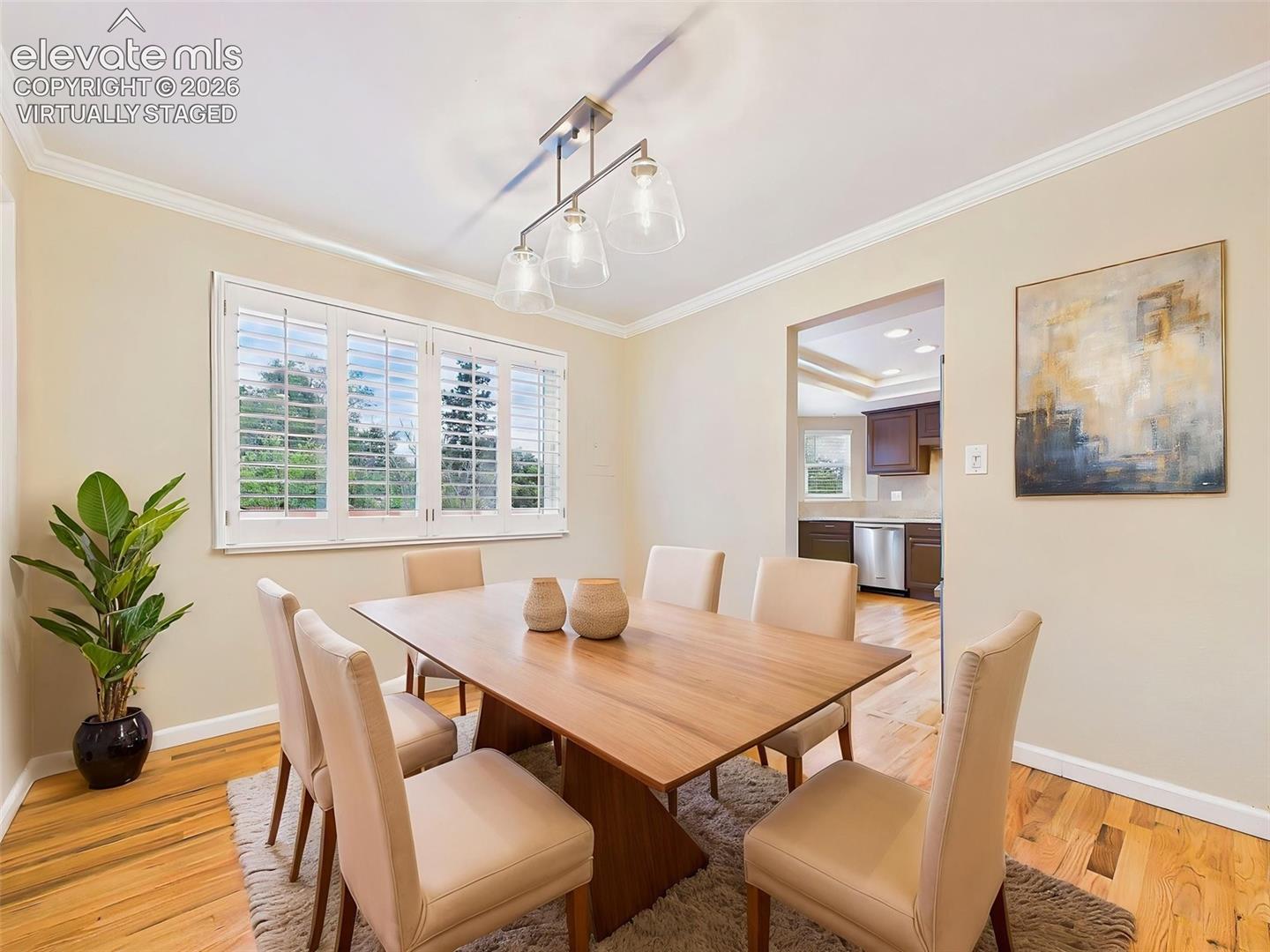 (Virtually Staged) Formal dining room with hardwood flooring, crown molding, and a modern light fixture, creating an inviting space for everyday meals and special occasions.