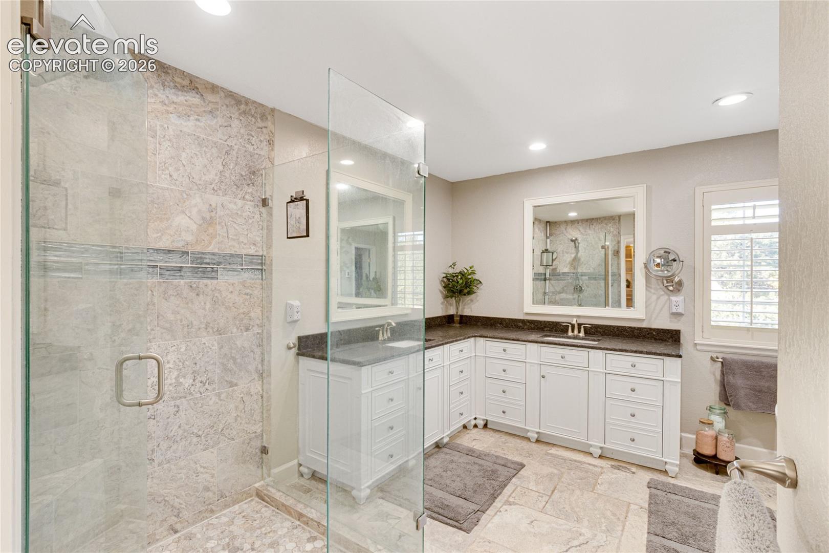 Walk-in shower with stone tile surround, glass enclosure, and pebble-style stone flooring