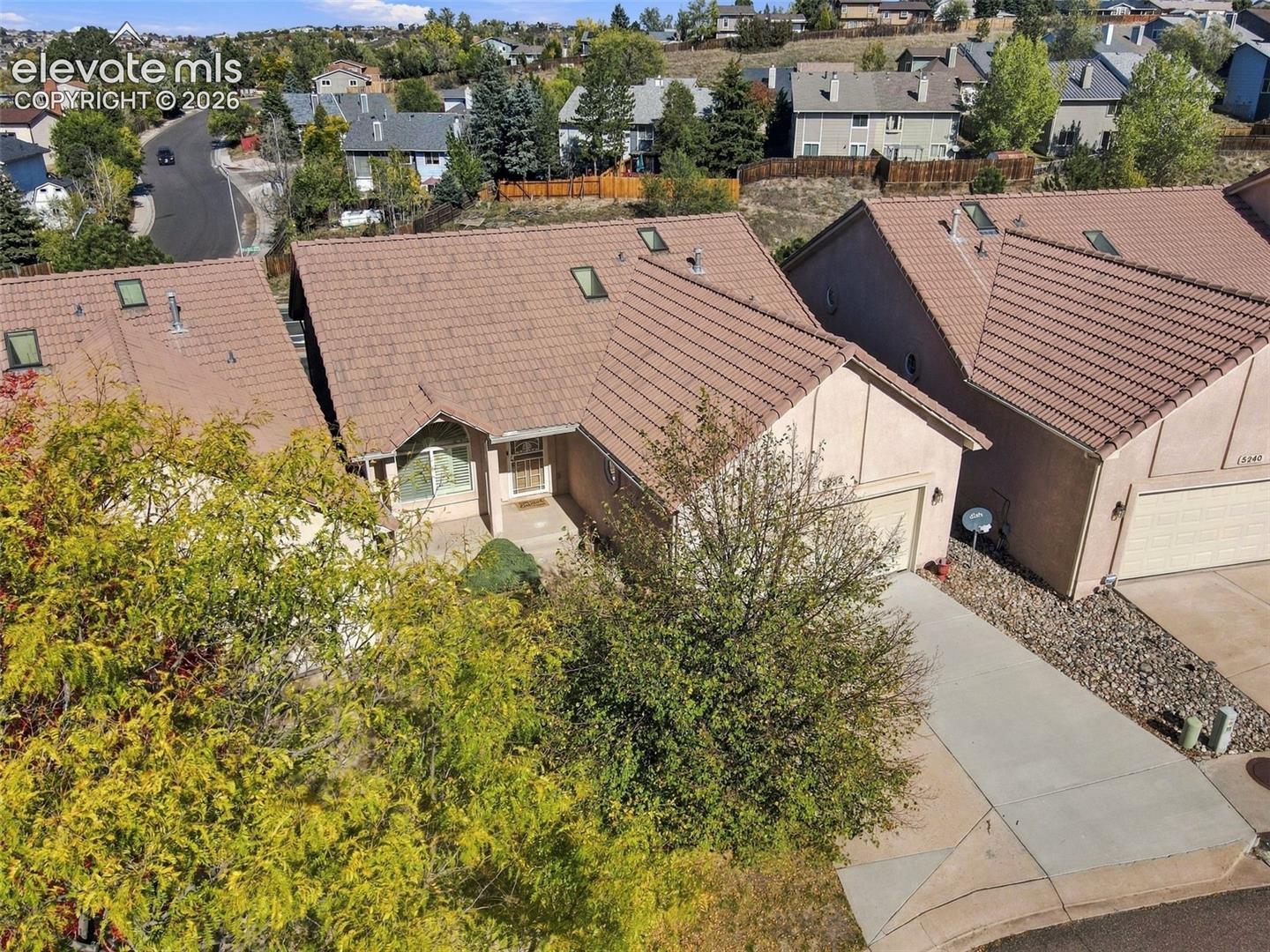 Aerial view of stucco exterior residence featuring a concrete tile roof, multiple skylights, and a paved driveway leading to an attached garage