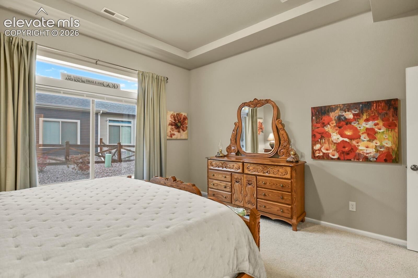 Room featuring a tray ceiling, large picture window, and wall-to-wall carpeting, sitting and dressing area