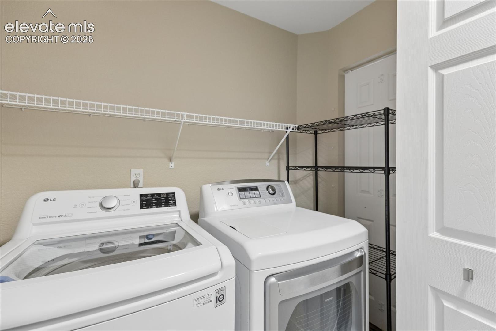 Laundry area featuring white top-load washer, front-load dryer, and wall-mounted wire shelving
