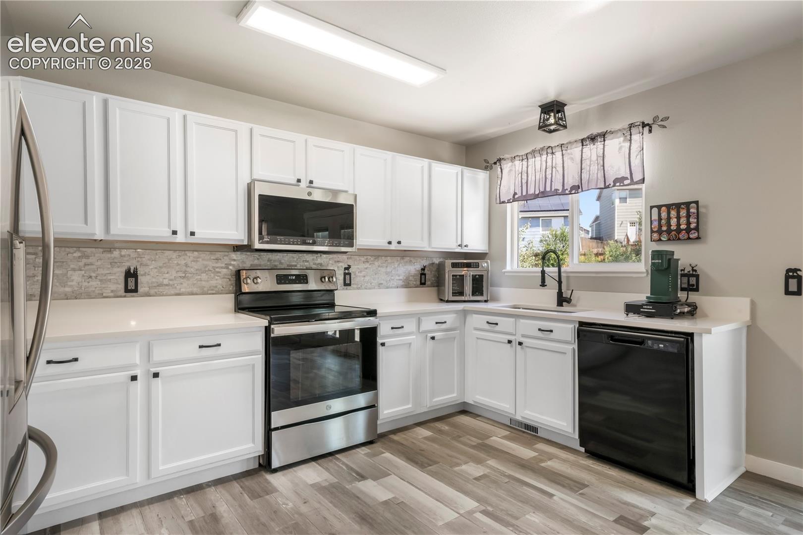 Kitchen with new LVP floors, stainless steel appliances and abundant cabinets and access out to patio