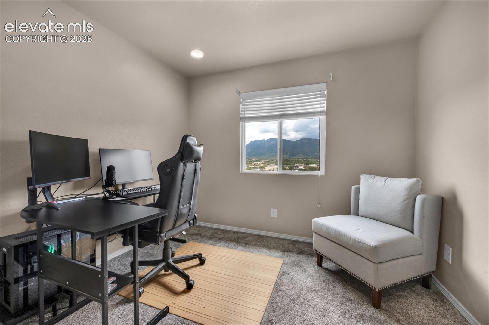 Bedroom #2 is currently being used as an office. Neutral tone wall paint and carpeted flooring in a versatile room