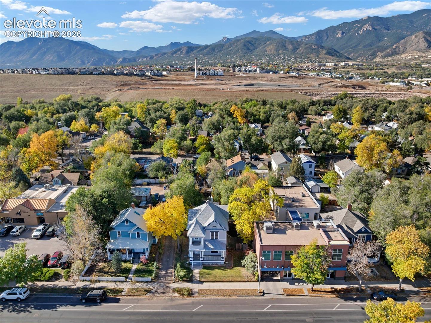 Aerial perspective of multi-story residences featuring pitched rooflines, covered front porches, and proximity to mature trees with mountainous terrain in the distance