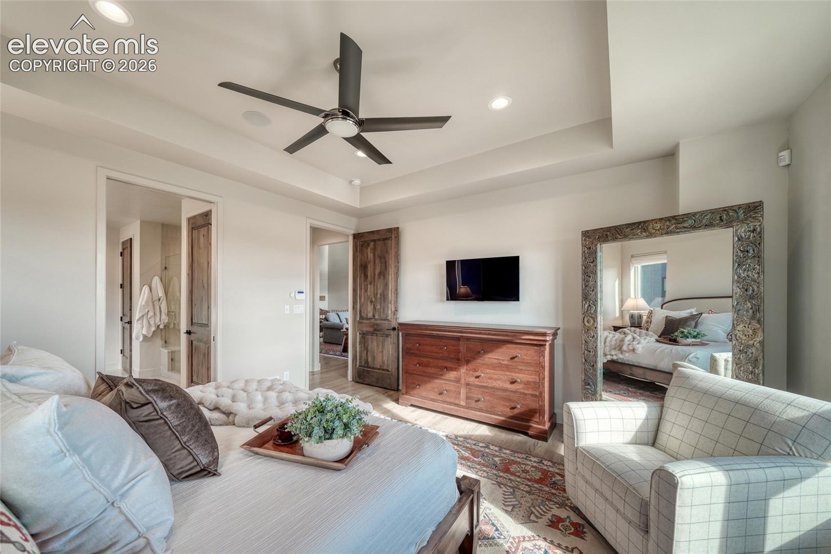 Tray ceiling featuring a contemporary ceiling fan, recessed lighting, and rustic wood-finish interior doors