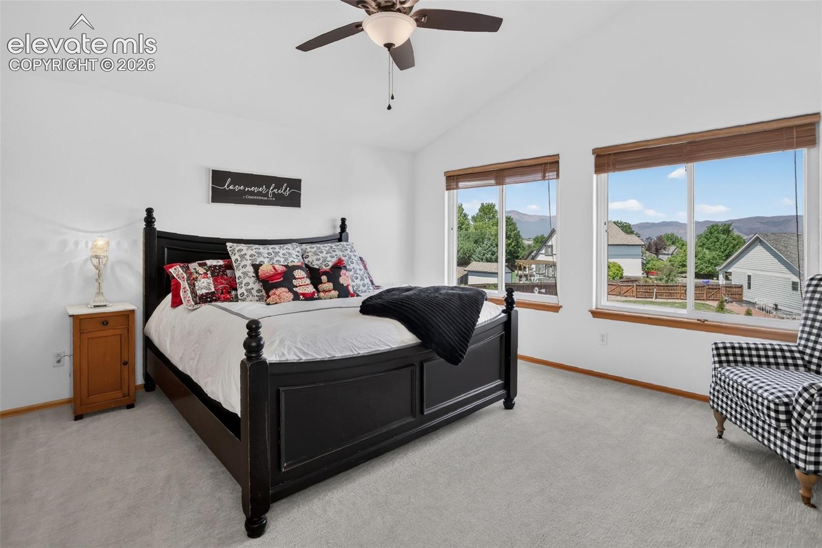 Carpeted interior space featuring a vaulted ceiling with a ceiling fan