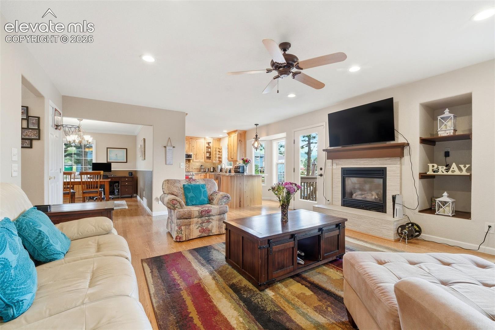 Living area featuring a gas fireplace with a stone surround, a wood mantel, and built-in shelving