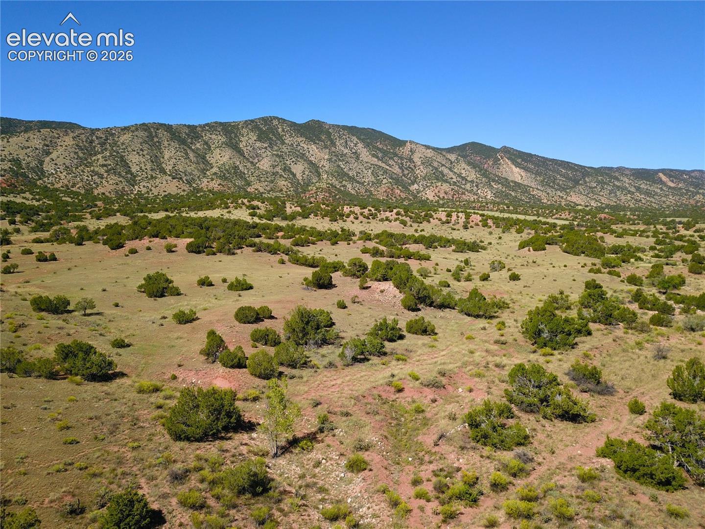 Expansive landscape featuring distant mountains, natural vegetation, and clear skies