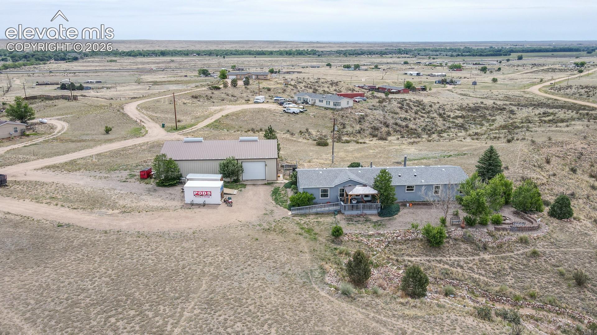 Expansive acreage featuring a single-story residence with a covered porch and a large detached garage/workshop