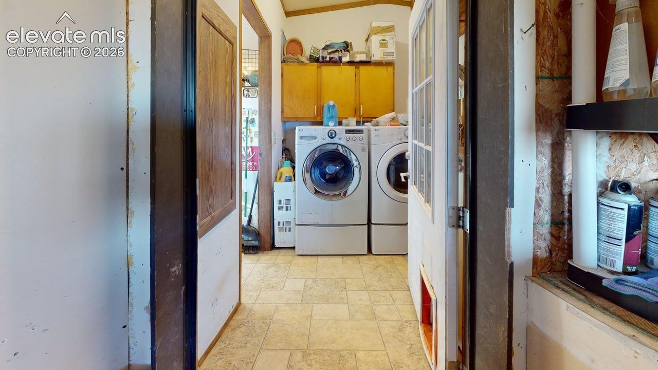 Laundry area with light stone finish flooring and cabinet space