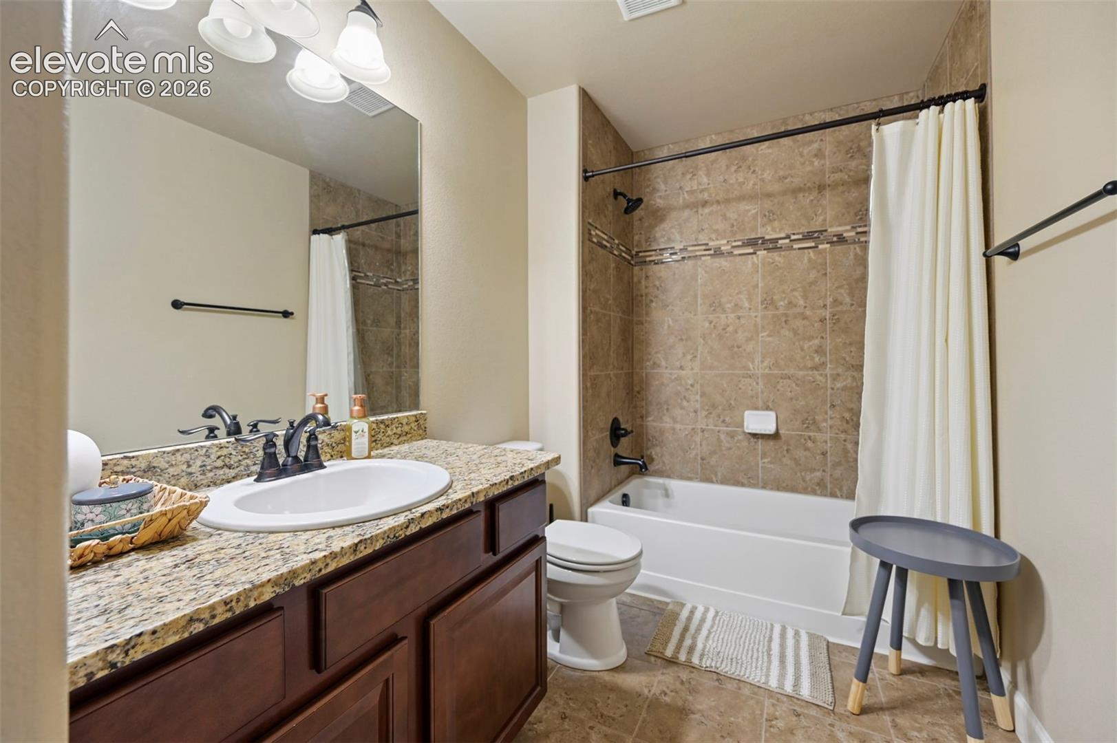 Vanity with granite-style countertop, undermount sink, and dark wood-finish cabinetry
