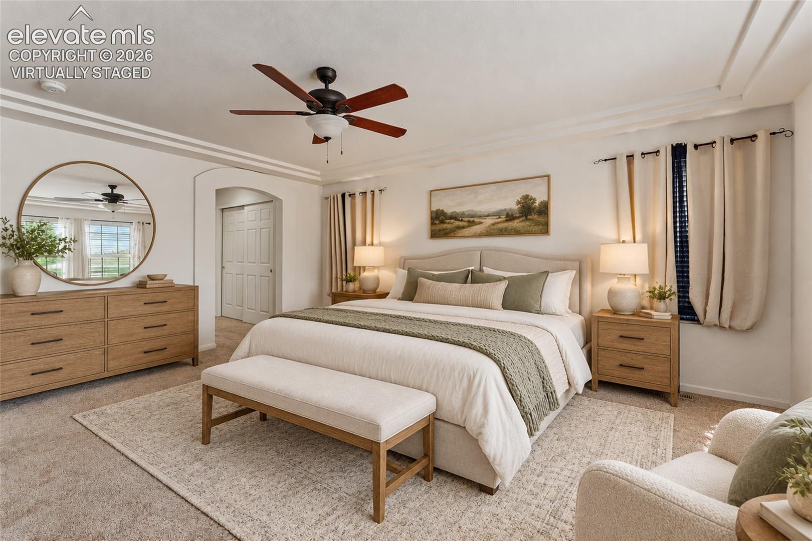 Virtually Staged Room featuring tray ceilings, neutral carpeting, an arched entryway, and a central ceiling fan with integrated lighting