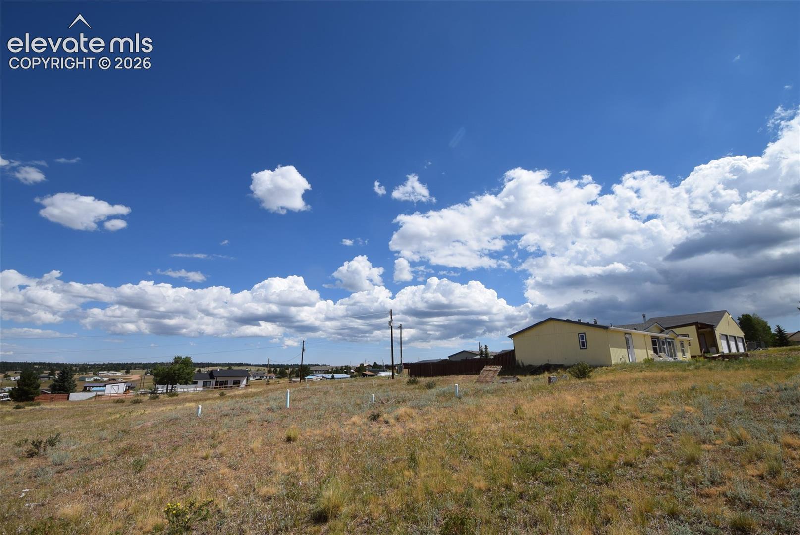 Expansive undeveloped lot featuring natural ground cover, a gentle slope, and distant structures