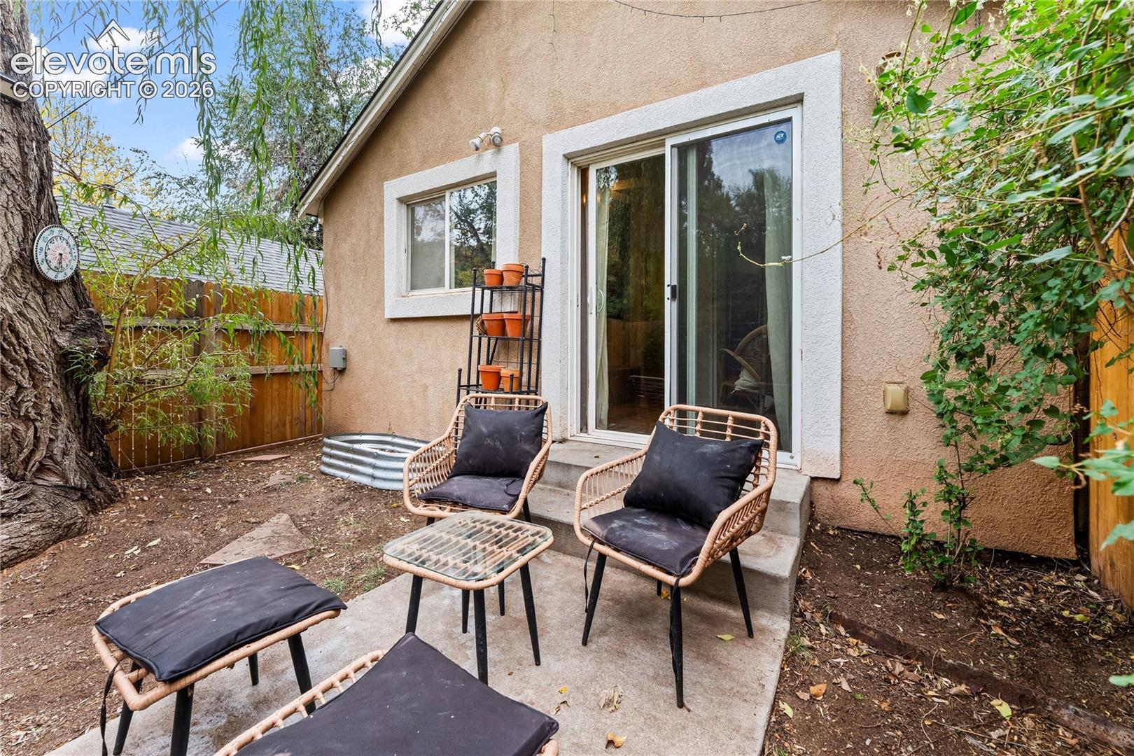 Stucco exterior featuring a concrete patio, sliding glass door, and wood fence perimeter