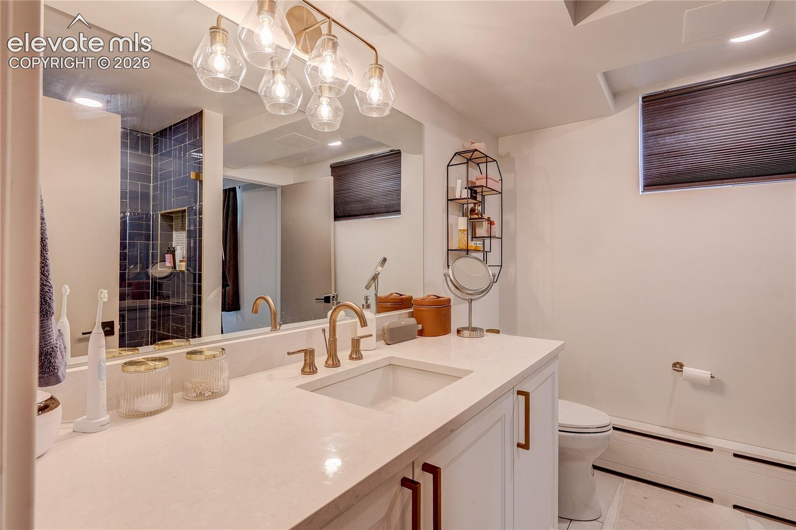 White vanity with integrated sink, gold-tone fixtures, and a large mirror