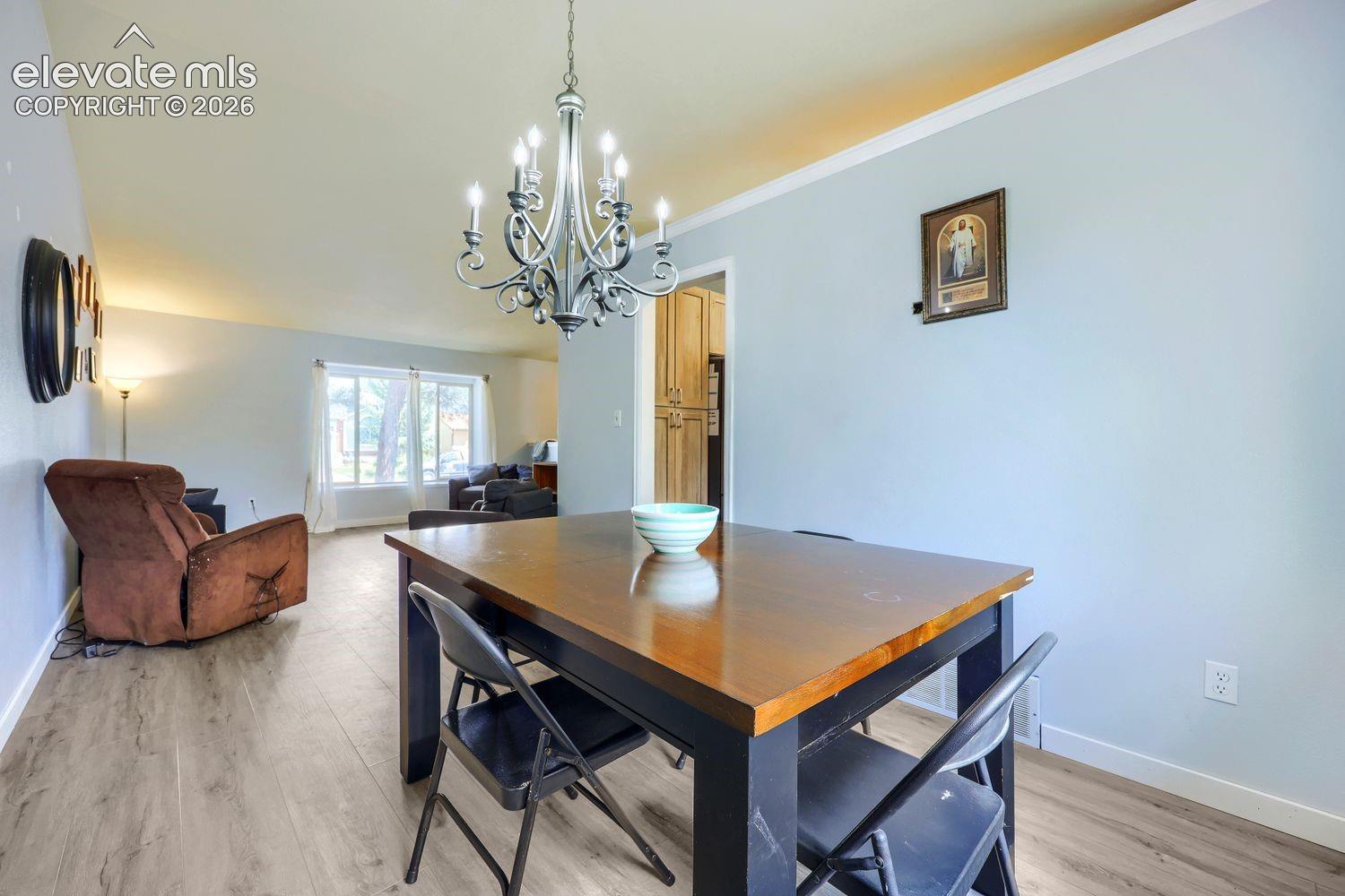 Chandelier lighting, wood-finish flooring, and white crown molding