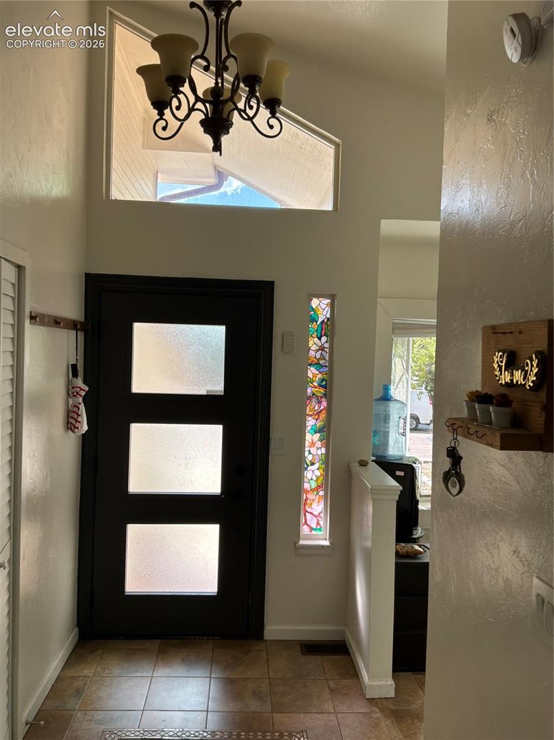 Entryway with tile flooring, a modern door featuring three frosted glass panels, and a decorative stained-glass sidelight