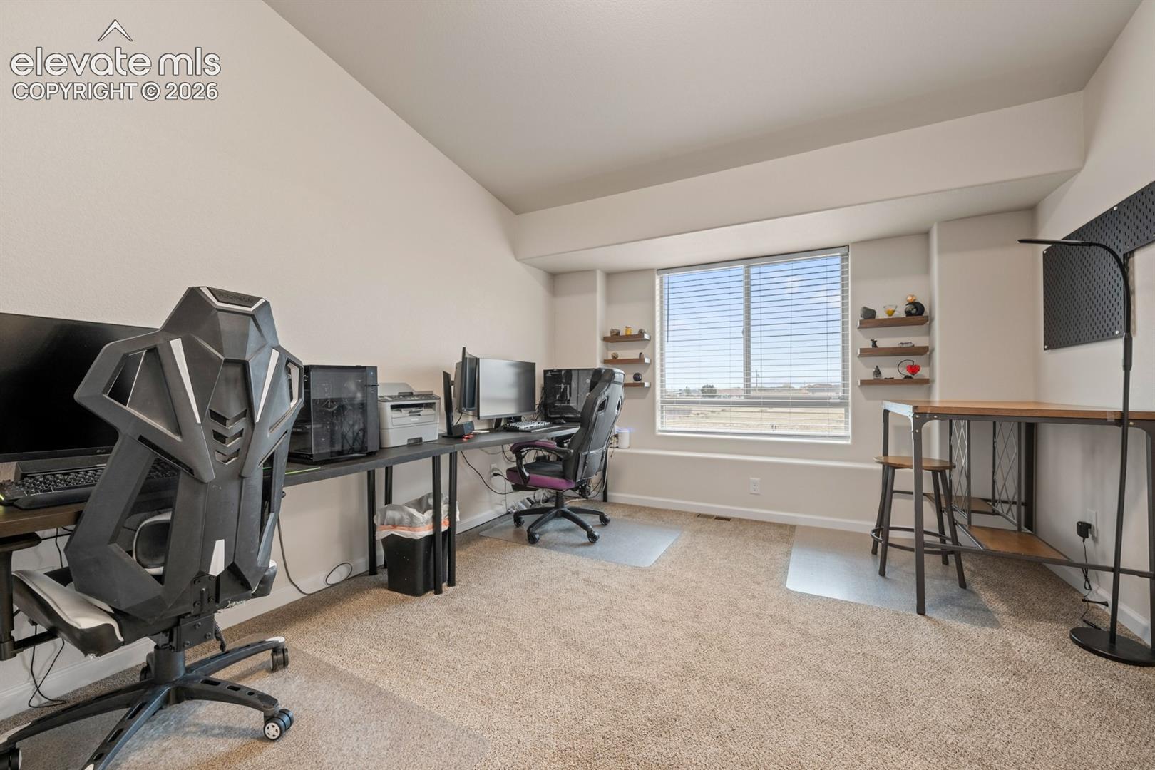 Neutral-toned room featuring a recessed window, wall-mounted wooden display shelving, and wall-to-wall carpeting