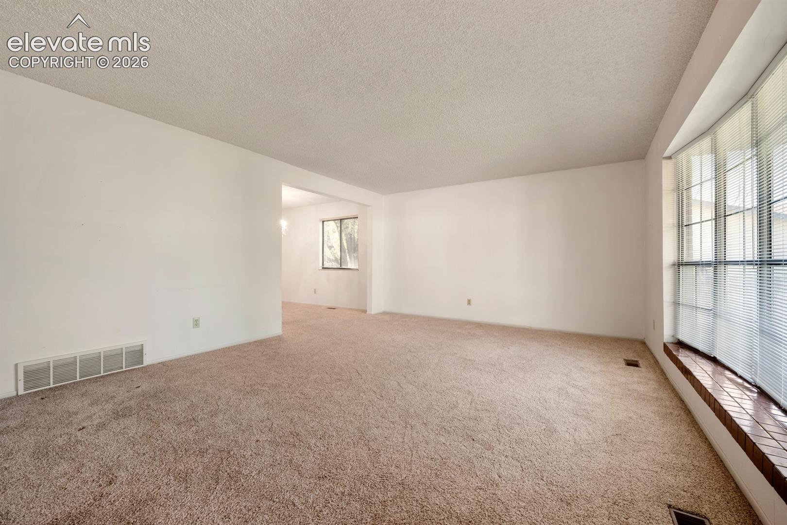 Living area featuring carpeted flooring and a bay window with a wood-finish ledge