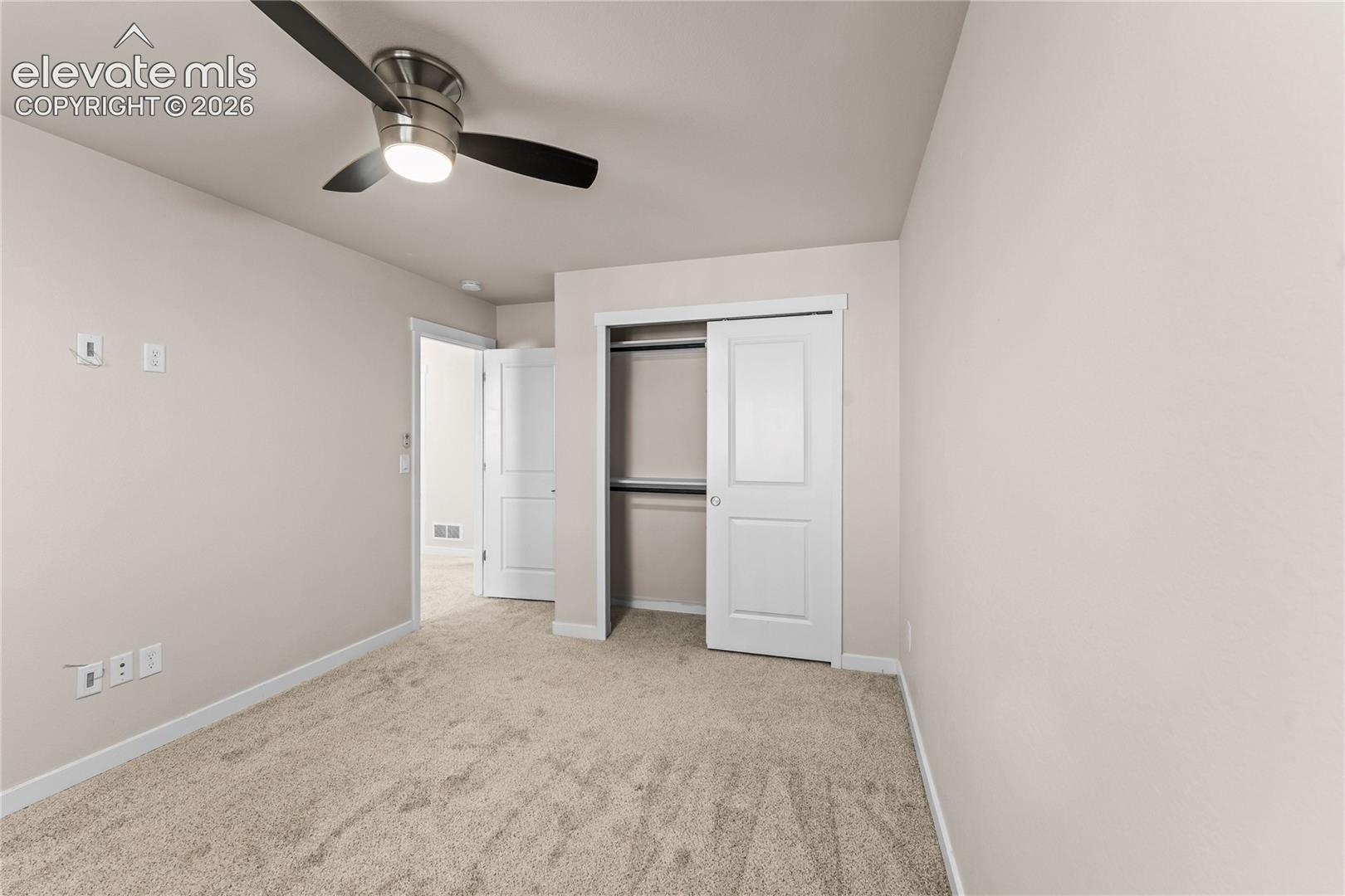 Room featuring neutral wall tones, neutral carpeting, a ceiling fan with integrated lighting, and a closet with a two-panel door