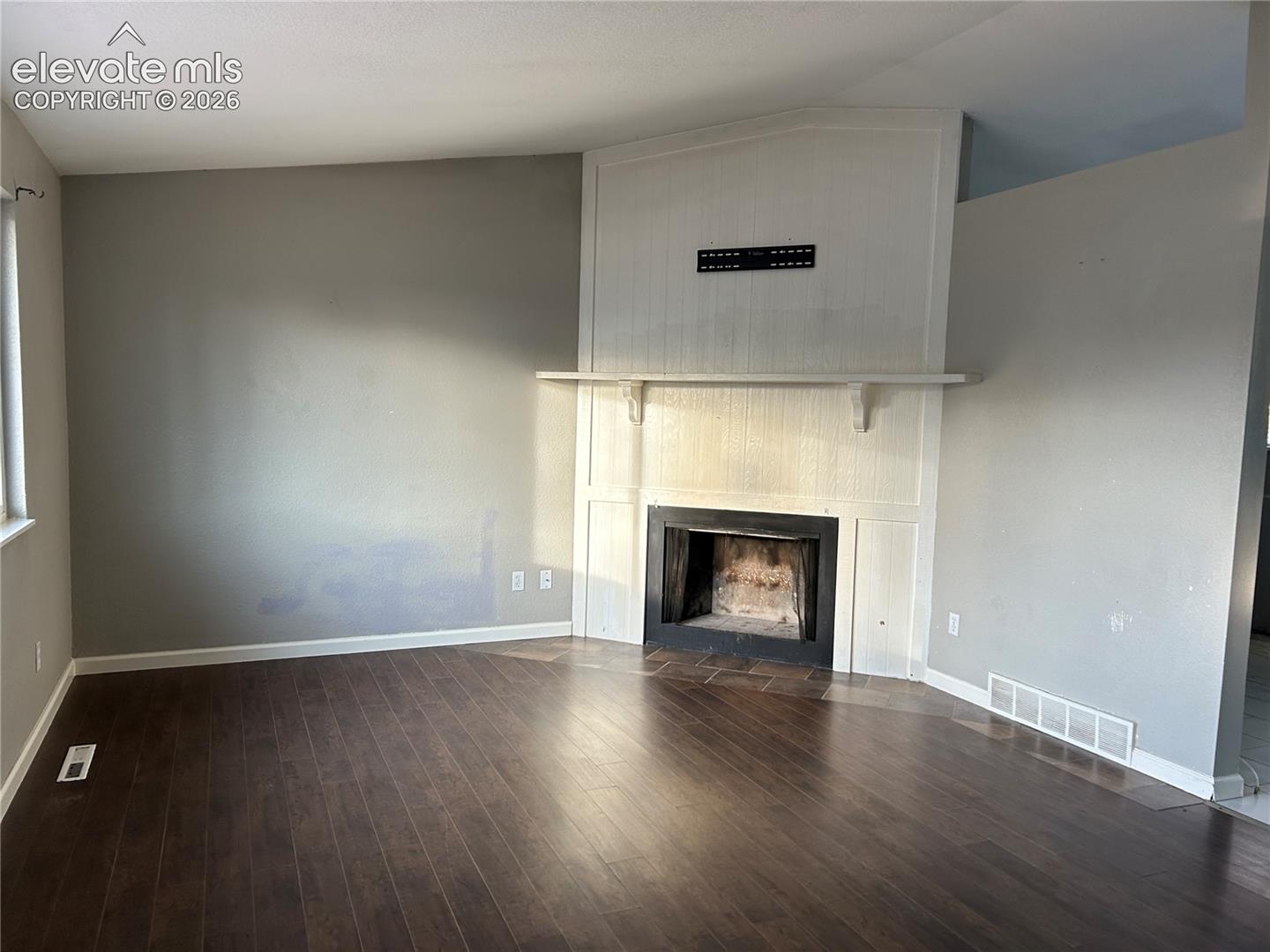 Wood-finish flooring throughout, featuring a fireplace with a white millwork surround and a stone-style hearth