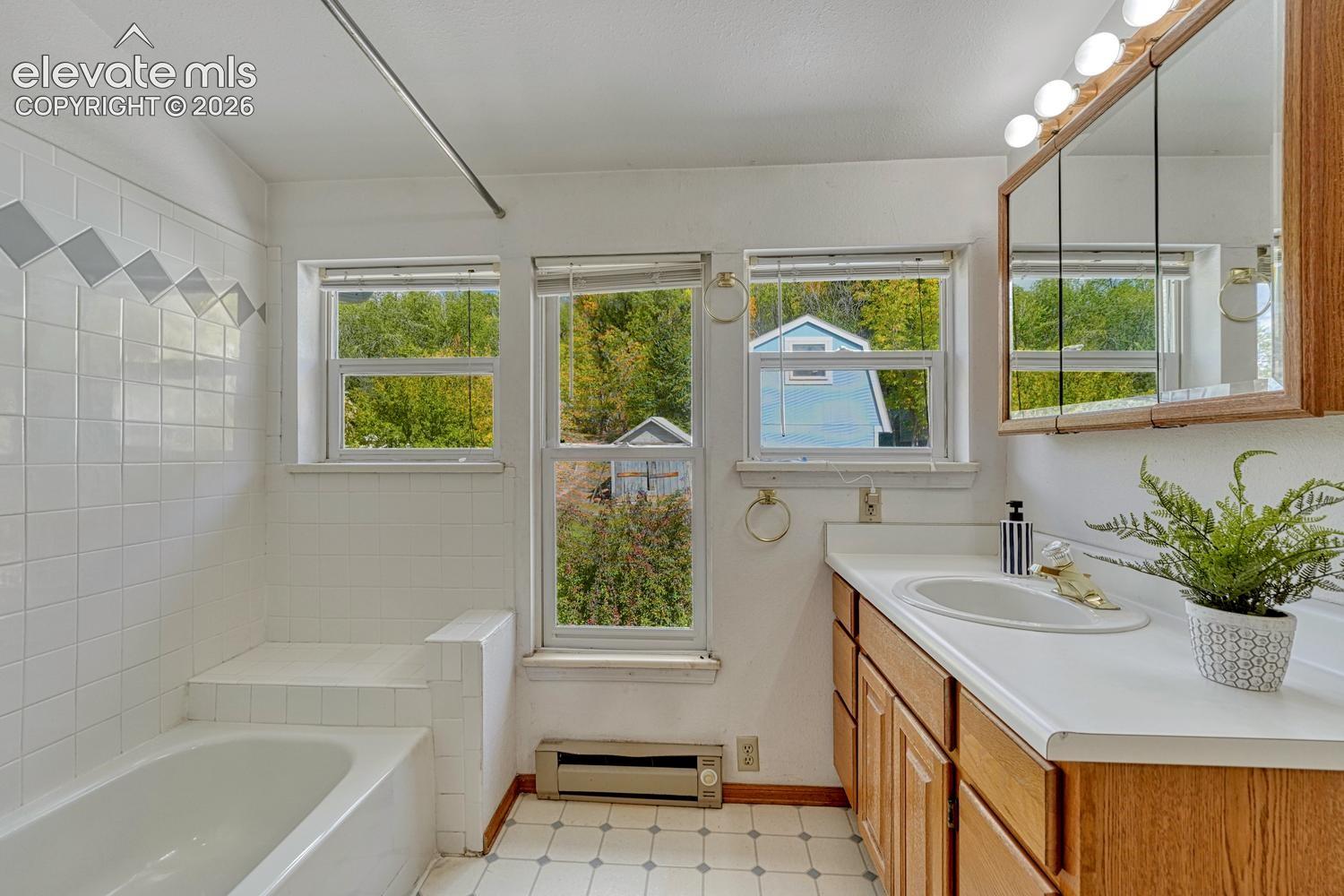 Built-in vanity with wood-finish cabinetry, white countertop, and integrated sink