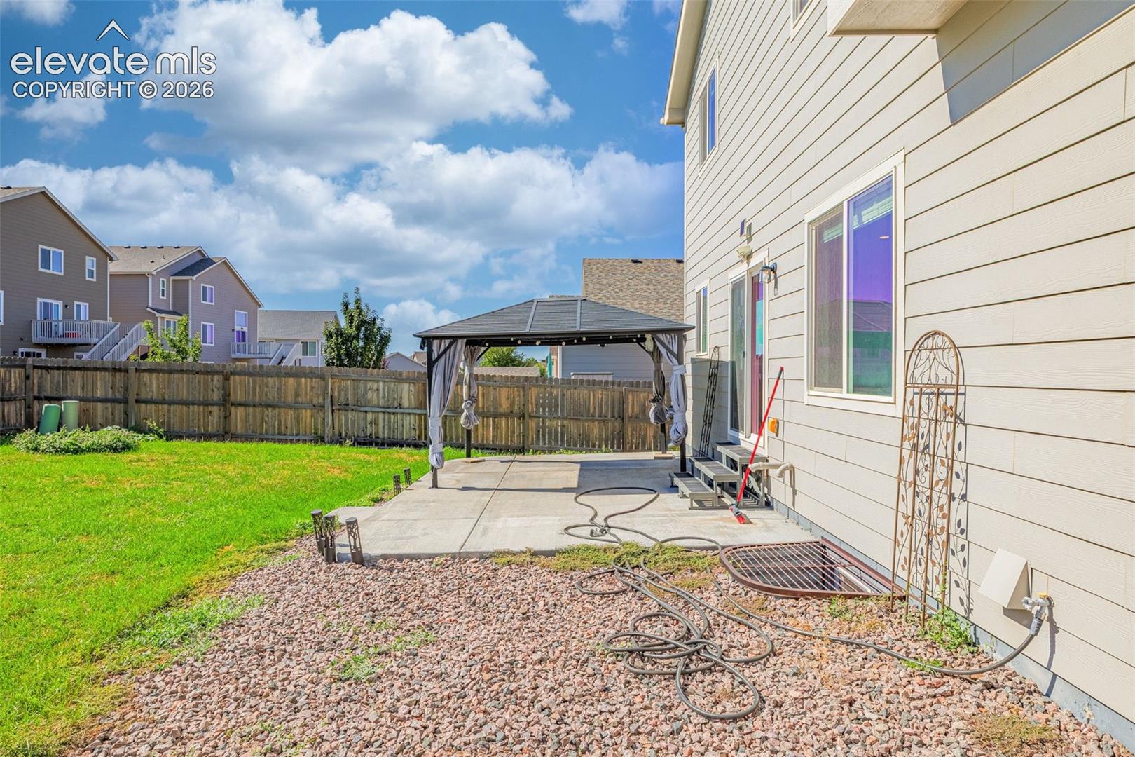 Expansive backyard with a level lawn, concrete patio, and privacy fencing