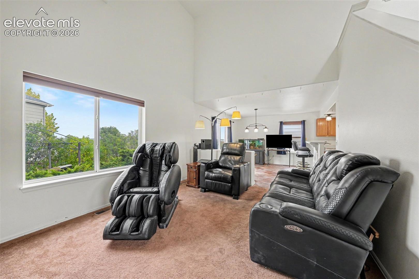 Living area featuring vaulted ceilings, large picture window, and wall-to-wall carpeting