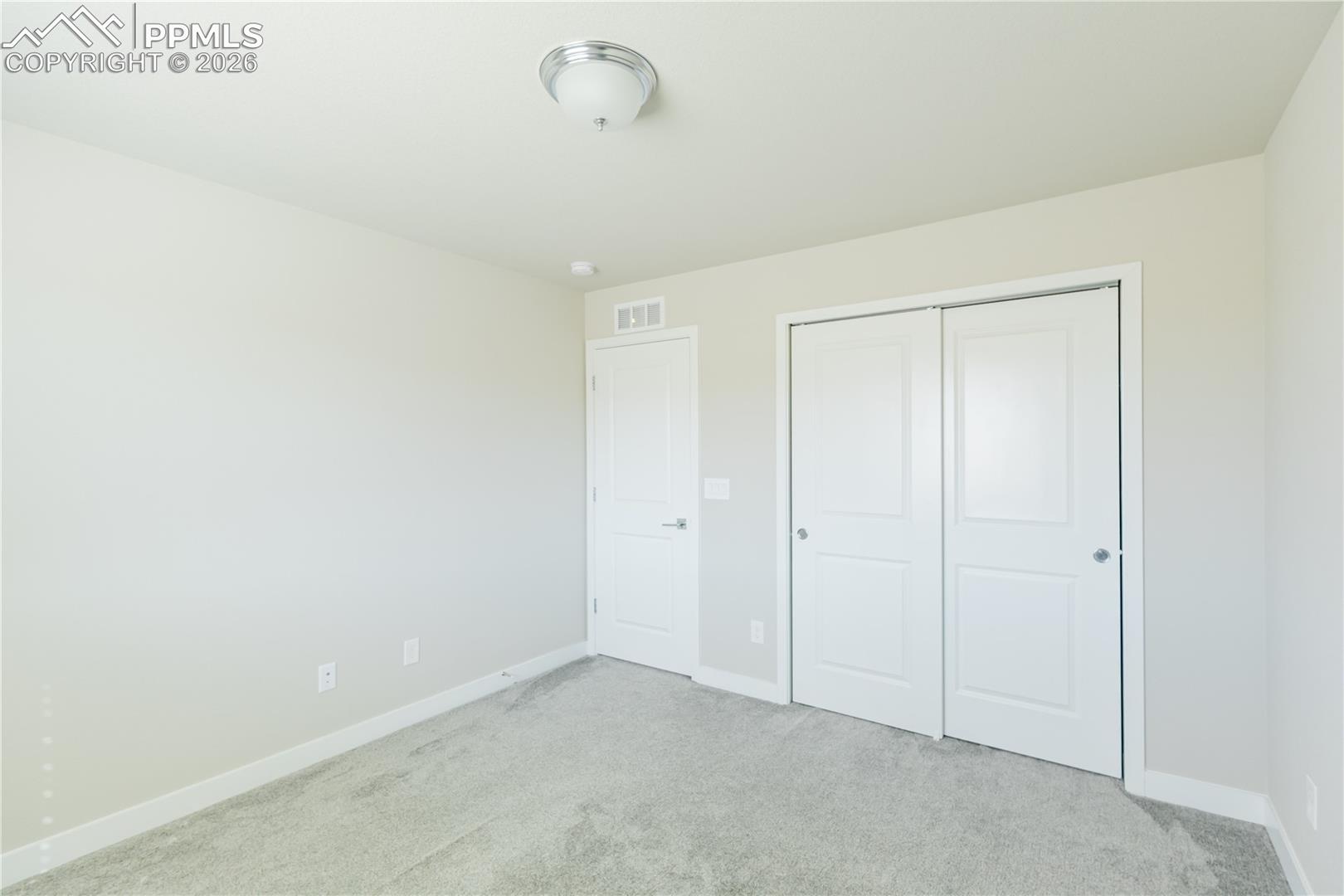 Unfurnished bedroom with light colored carpet and a closet