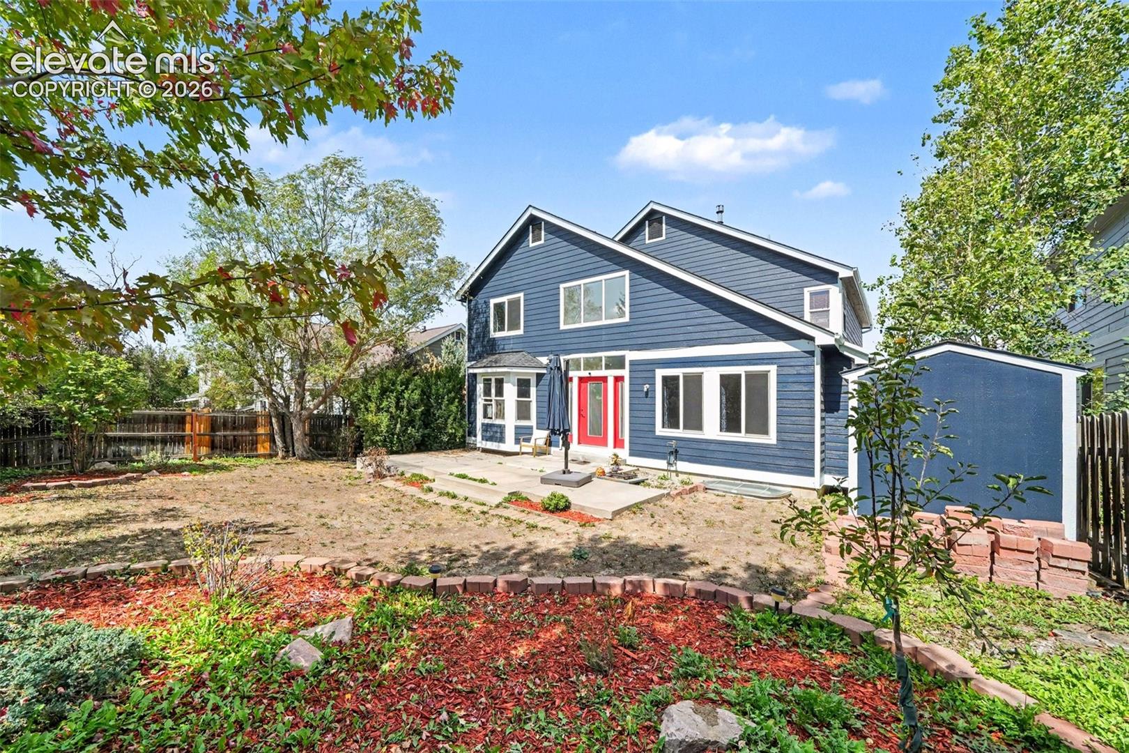 Expansive rear yard featuring a large patio, built-in garden beds, and a detached storage shed