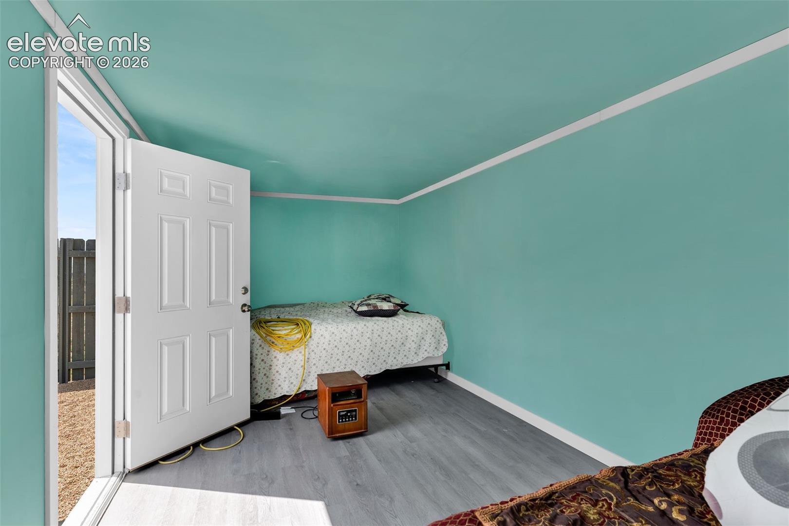 Interior space featuring vibrant blue-green walls, white trim, and wood-finish flooring