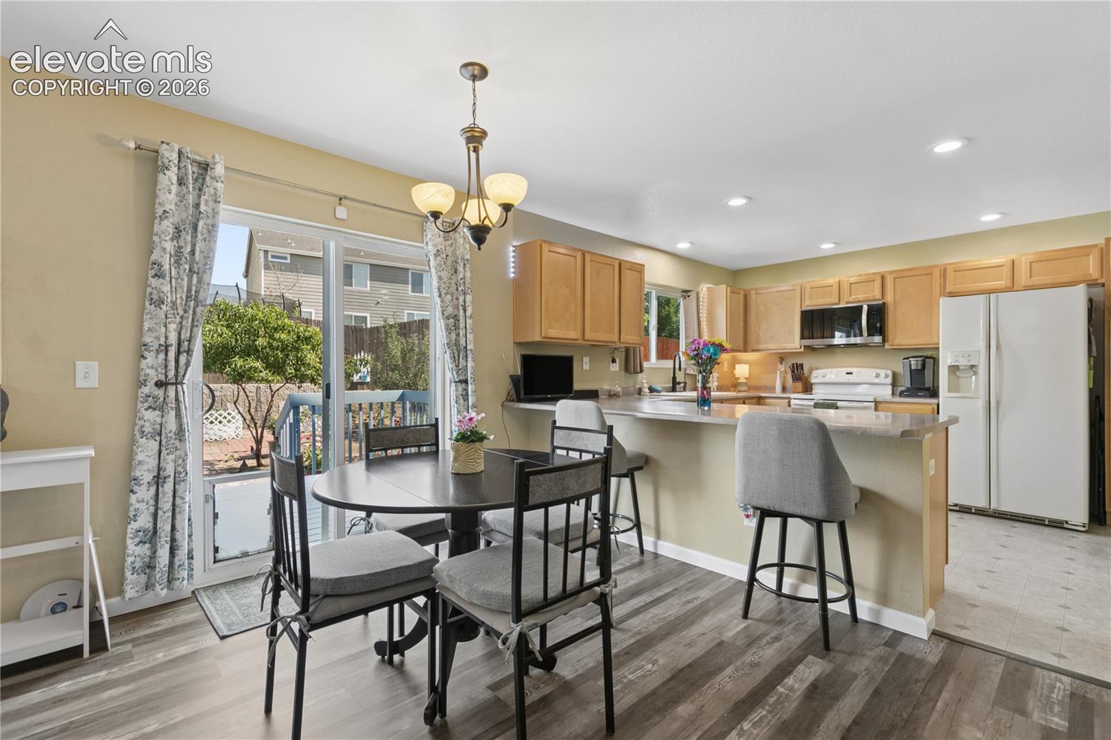Wood-finish flooring, recessed lighting, wood cabinetry, built-in microwave, and sliding glass door