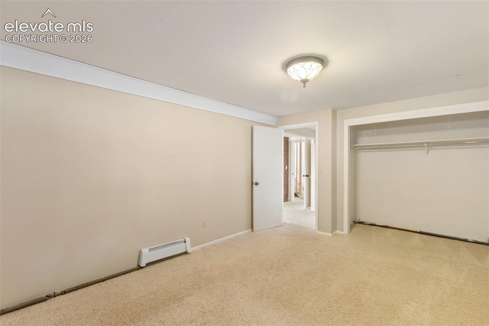 Wall-to-wall carpeting, crown molding, and a built-in closet with shelving and hanging rods
