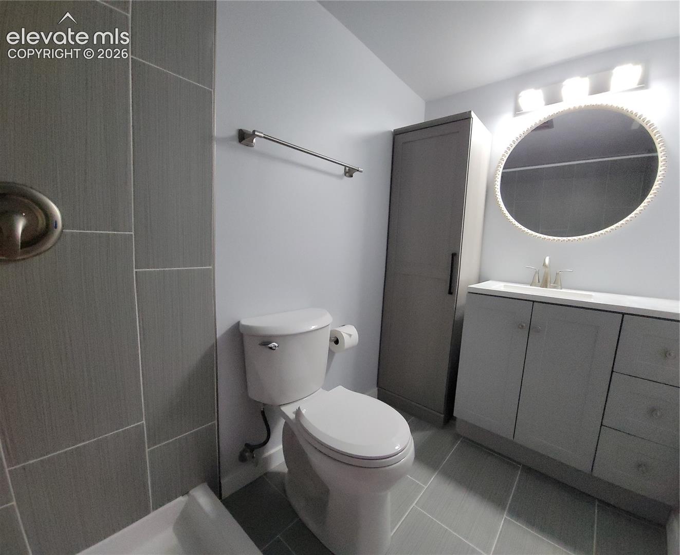 Primary Bathroom featuring light gray wall paint, a white toilet, and gray tile flooring