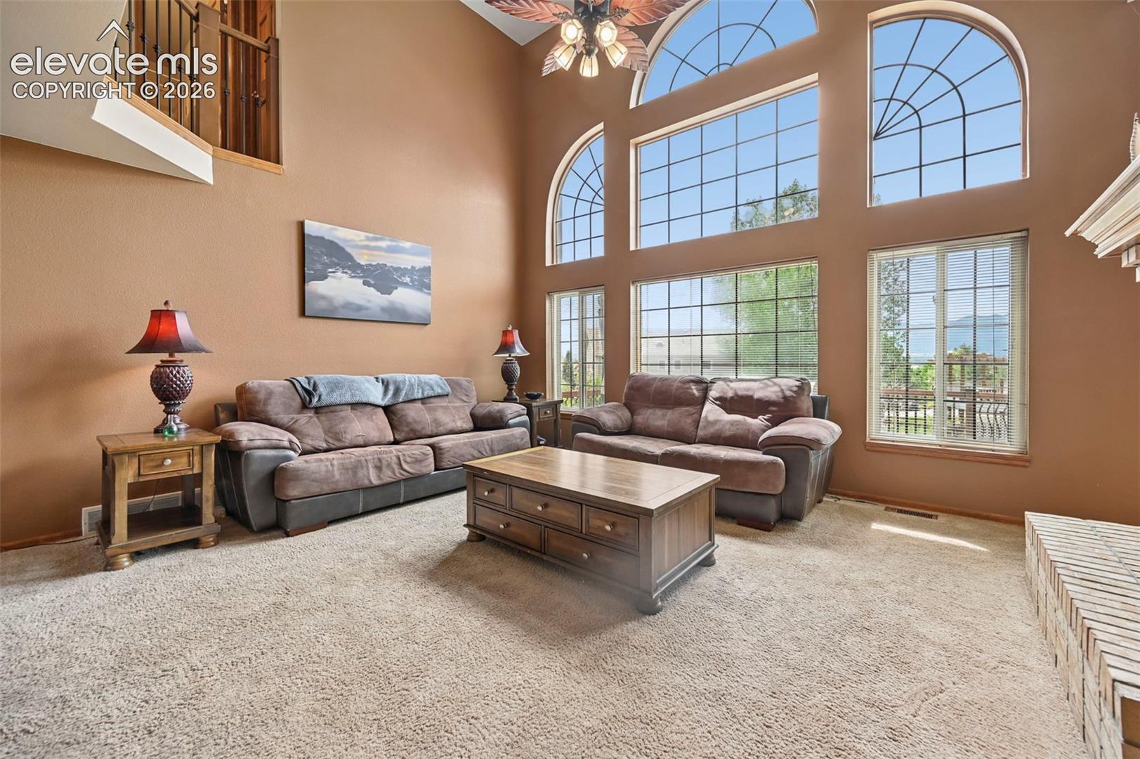 Two-story family room with high ceilings, arched transom windows, and an upper-level railing