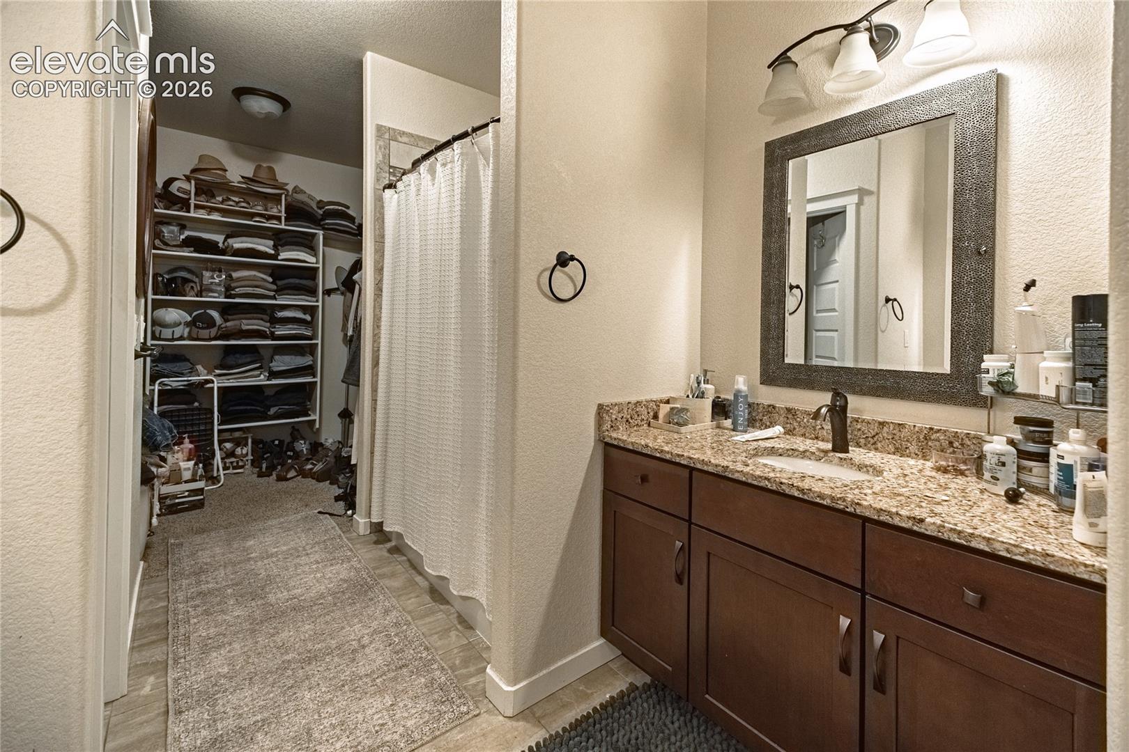 Vanity featuring a stone-composite countertop, undermount sink, dark wood-finish cabinetry, and a framed mirror