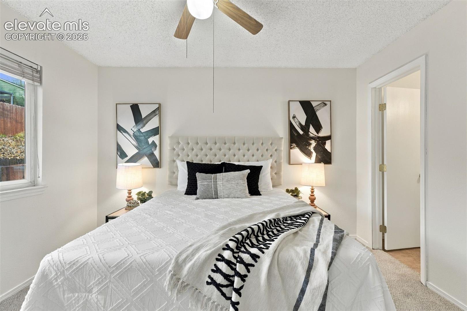 Neutral interior featuring light-toned wall paint, neutral carpeting, and a ceiling-mounted light fixture with wooden blades