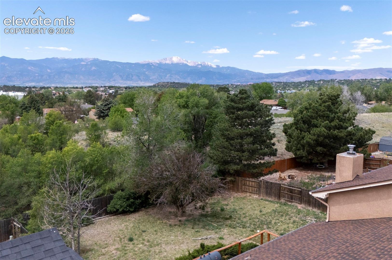 Expansive backyard featuring a wood fence, mature trees, and natural landscaping