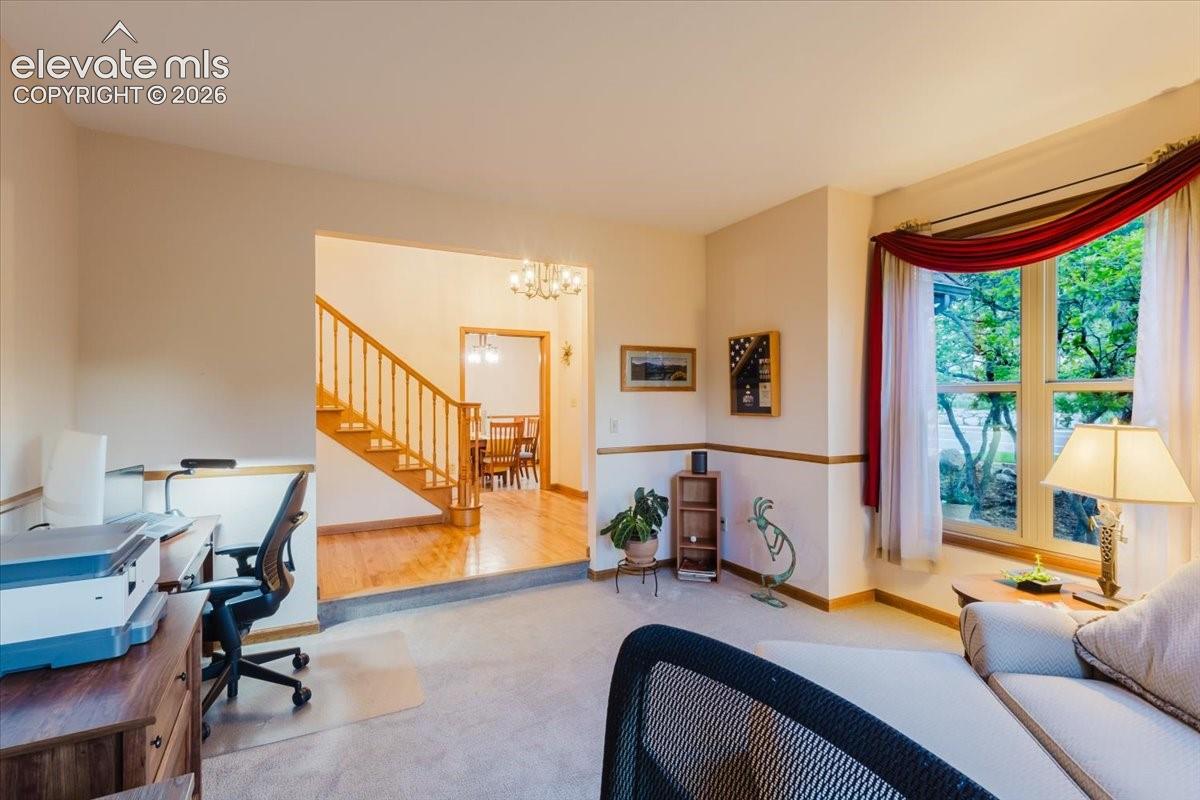 Carpeted living area with a large bay window, stairway access to upper level, and an adjacent dining area